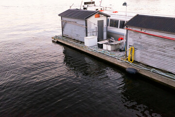 Small wooden dock buildings and mooring equipment sit beside calm water at a marina in Stockholm.