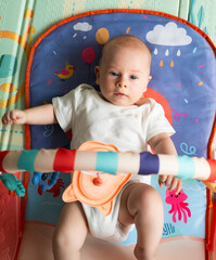 Fototapeta premium A baby is laying on a mat with a toy in his hand