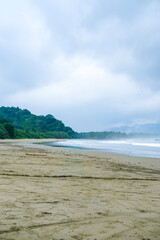 Cloudy atmosphere over Rajegwesi Beach in Banyuwangi features wide sandy shores, gentle waves, and forested hills, serving as a quiet coastal retreat and boat transit point to Green Bay. South Java.