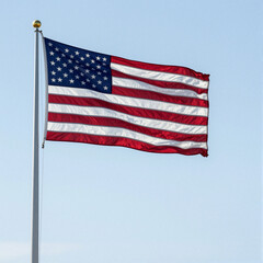 Fototapeta premium United States flag waving in the wind against a clear blue sky