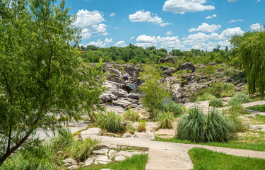 A path leads through a grassy area with a small stream