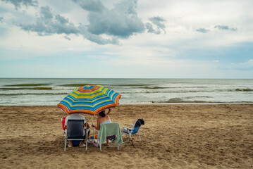 A group of people are sitting on chairs on a beach