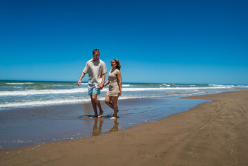 A man and woman are walking on the beach