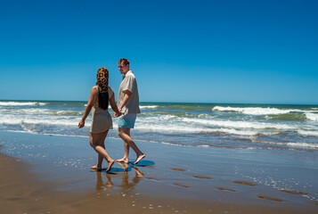A man and a woman are walking on the beach