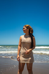A woman wearing a dress stands on the beach