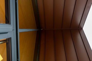 Obraz premium Gros plan sur un bardage métallique brun aux lignes verticales, offrant une texture moderne idéale pour illustrer une façade contemporaine.