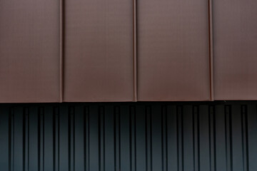 Gros plan sur un bardage métallique brun aux lignes verticales, offrant une texture moderne...