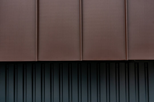 Gros plan sur un bardage m&eacute;tallique brun aux lignes verticales, offrant une texture moderne id&eacute;ale pour illustrer une fa&ccedil;ade contemporaine.