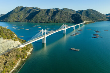 Obraz premium Winter aerial view of Bizen Hinase Bridge and oyster farming rafts in Seto Inland Sea, Japan.