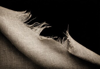 暗い背景にほつれたエッジを持つ生地はテクスチャを示します