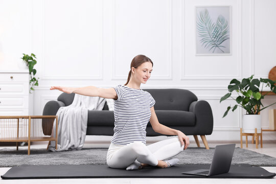 Pregnant woman having online yoga class via laptop at home