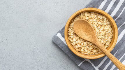 Oats in wooden bowl with wooden spoon on striped kitchen towel create cozy and inviting atmosphere