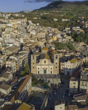 Aerial view of the grand church standing proudly amidst a sea of terracotta rooftops, nestled against the backdrop of rolling green hills, Caccamo, Sicily, Italy.