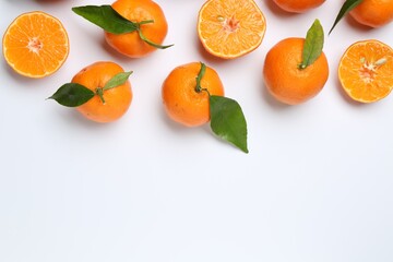 Fresh ripe tangerines and green leaves on white background, flat lay. Space for text