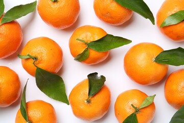 Fresh juicy tangerines and green leaves on white background, flat lay