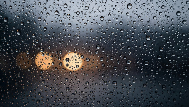 Raindrops on glass at night with blurred city lights in the background, creating a cinematic and moody urban scene. - Powered by Adobe
