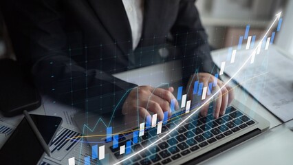 A business professional engages in financial analysis using a laptop, surrounded by graphs and charts that represent growth and market trends in a modern office setting. Copula