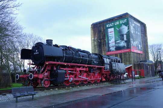Emden, Germany - Jan 1 2026 Memorial steam Locomotive stands in front of a High bunker from WWII near the station. This freight locomotive was built in 1943 by Batignolles-Chatillon