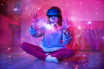 Child girl wearing virtual reality headset and looking at digital space system with planets or Universes. Space exploration with augmented reality glasses. She is sitting on flor at childroom.