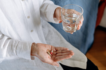 Person Holding Pills And Glass Of Water In Calm Home Setting For Health And Wellness