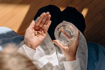 Person Holding Pills And Glass Of Water In Calm Home Setting For Health And Wellness