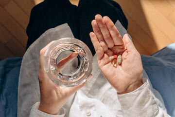 Person Holding Pills And Glass Of Water In Calm Home Setting For Health And Wellness