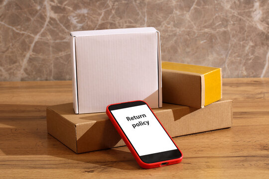 stack of boxes on table and smartphone with Return policy on screen. return of product online.