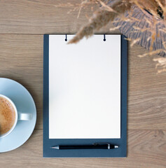 Flat lay of blank notebook page with pen and coffee on wooden table, minimal workspace concept for planning, to do lists, goals, resolutions, notes, journaling and personal organization