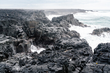 rough seas on a stretch of coastline with black volcanic rocks and rough seas on the Reykjanes Peninsula in Iceland on a spring day.