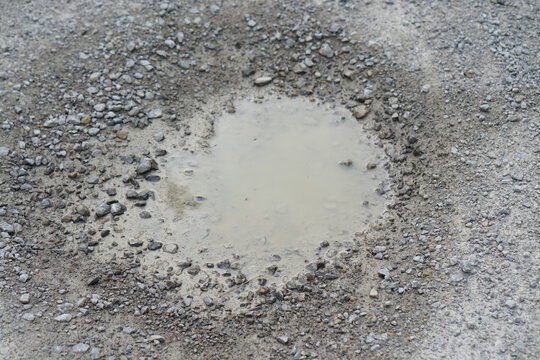 small puddle of muddy water in gray gravel and stones on construction site ground with wet soil and rocks after rain outdoor industrial environment infrastructure. - Powered by Adobe