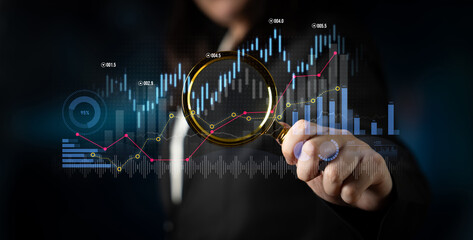 A business professional uses a magnifying glass to examine digital financial graphs and statistics,...