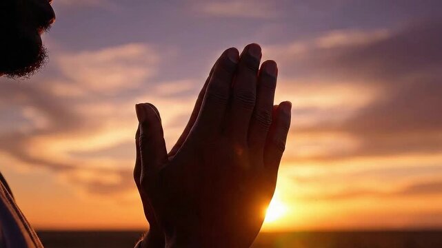 Silhouette of man praying hands, peaceful and spiritual, devotion and hope concept against dramatic sunset sky background