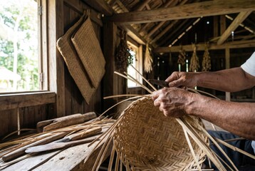 Crafting a basket using traditional weaving techniques in a rural workshop during daylight hours
