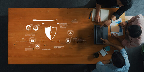 Three professionals engage in a collaborative discussion on cybersecurity strategies, highlighting data visualizations and security icons in a modern workspace. Trope
