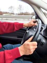 The driver's hands on the steering wheel of a car while driving