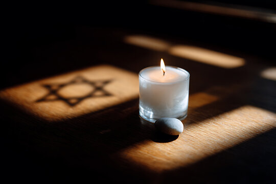 spiritual still life, minimalist flat lay with white candle, small pebble and star of davids shadow on dark wood, creating a respectful composition