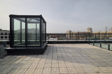 Glass elevator perched above city skyline on neutral terrace