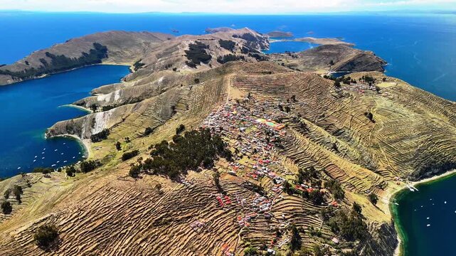 Aerial drone view of the Island of the Sun on Lake Titicaca in Bolivia. Isla del Sol in the Andes Mountains. A landscape with a small village surrounded by deep blue water. 
