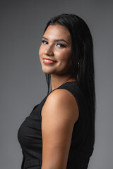 Fototapeta premium Studio portrait of smiling Hispanic business woman looking over shoulder