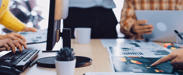 A diverse group of professionals collaborates in a modern office setting, discussing data insights and displaying various charts and documents on a wooden table. SACTR