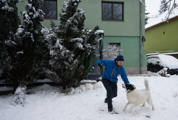 Man playing with dog in snowy backyard during winter
