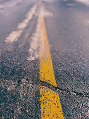 Ligne jaune sur une route asphalt&eacute;e d&eacute;fonc&eacute;e en hiver. Fond abstrait.