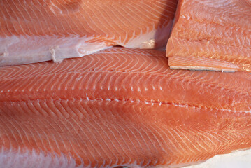 A fresh raw salmon fillets arranged in layered slices, showcasing vibrant pink flesh and crisp white marbling. Ideal for seafood, market displays, groceries, recipes