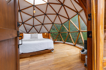 Open wooden door to geodesic dome glamping bedroom with view © STOCKEROcr
