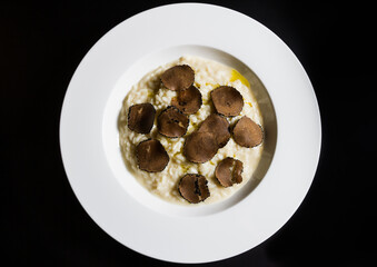 Plate of Italian risotto with truffle on a black background. Top view.
