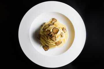 Plate of Italian pasta with truffle on a black background. Top view.