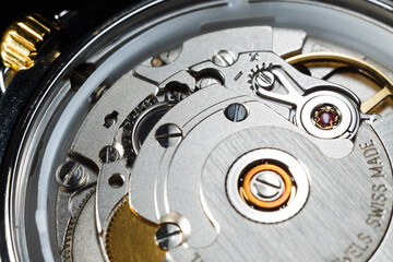 Extreme close-up of a luxury mechanical watch movement with visible gears, jewels, and balance wheel. Inscription: made in Switzerland.