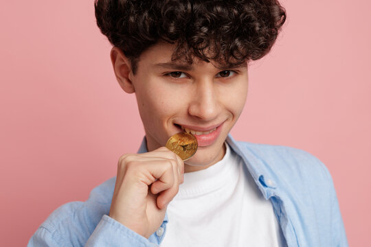 Young man biting digital coin cryptocurrency investment and fintech lifestyle concept on pink background - Powered by Adobe