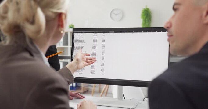 Team colleagues in office meeting discuss data. They analyze a spreadsheet on a computer monitor, noting key figures for a modern business office. Concept of teamwork and data analysis.
