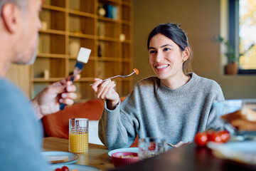 Happy, smiling woman sharing a healthy breakfast with her partner at home, enjoying fresh food and morning conversation